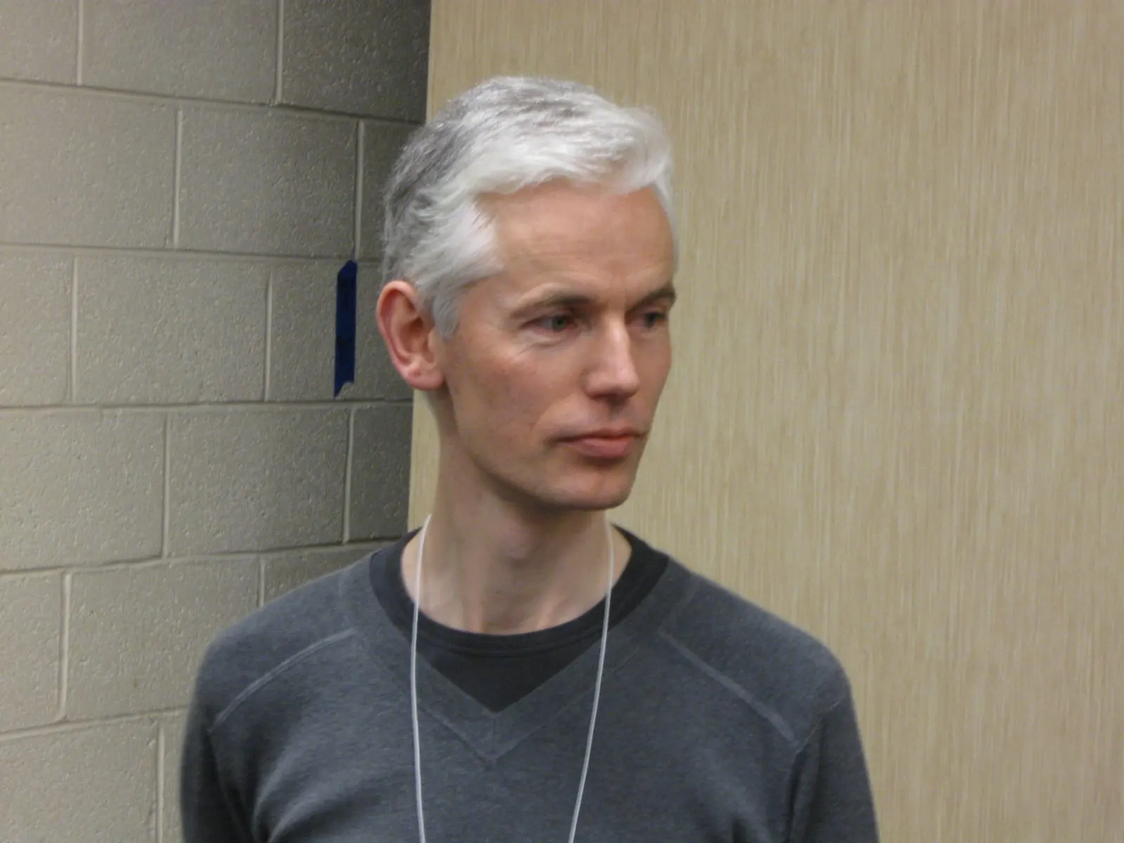 Timothy Gowers, with grey hair and a dark sweater, looking to the side in a hallway.