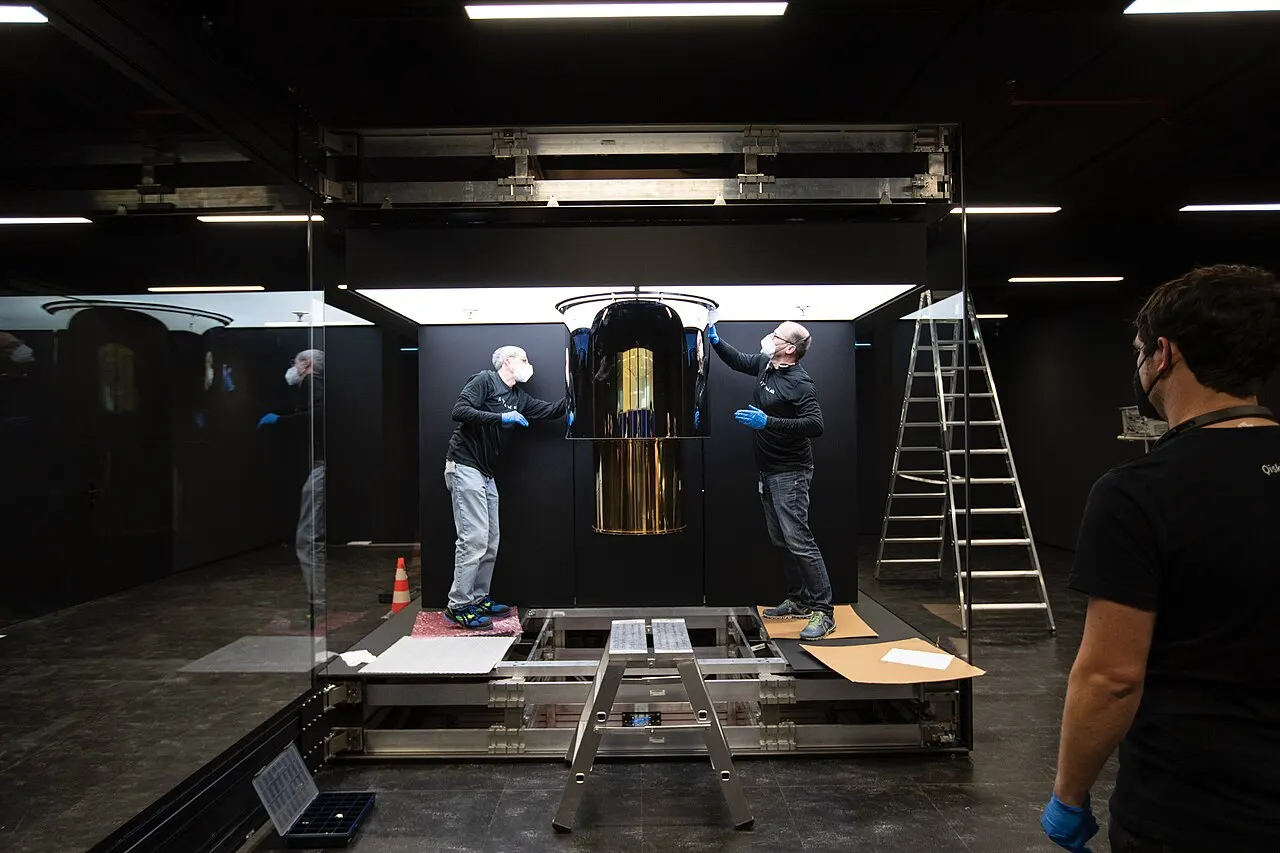 IBM engineers working on the IBM Quantum System One, a large cylindrical machine inside a glass enclosure